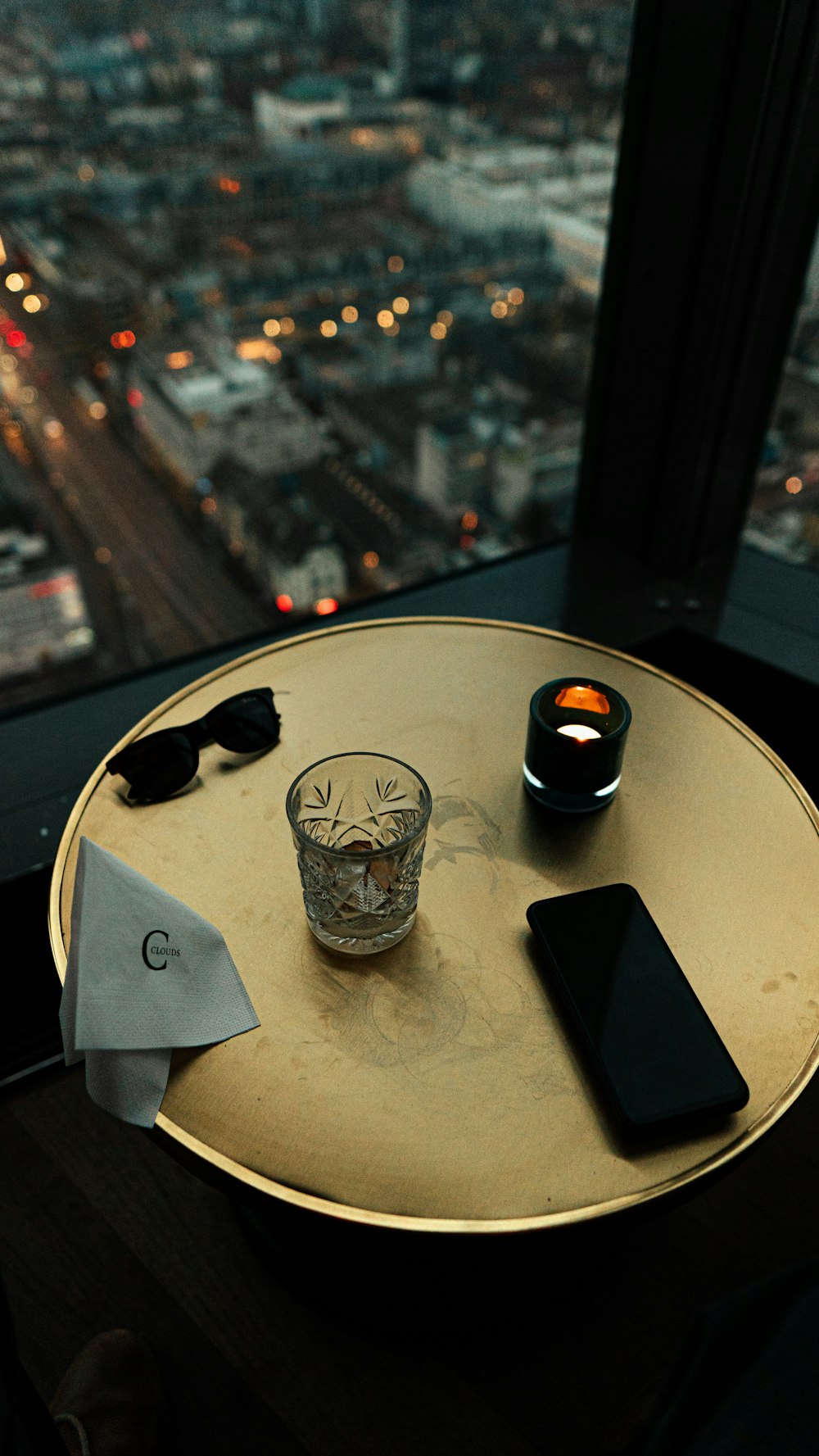 a table with a cell phone and a glass on it