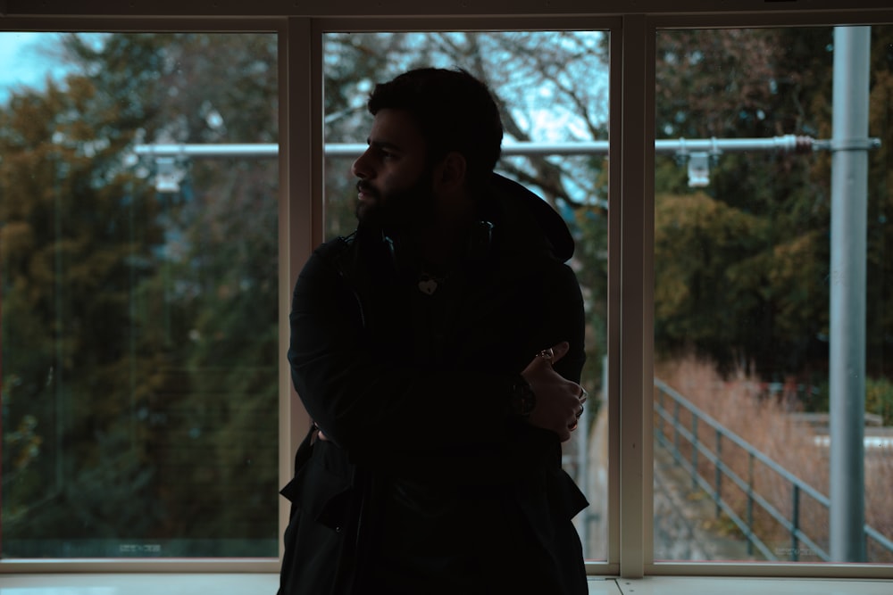 a man standing in front of a window with his arms crossed