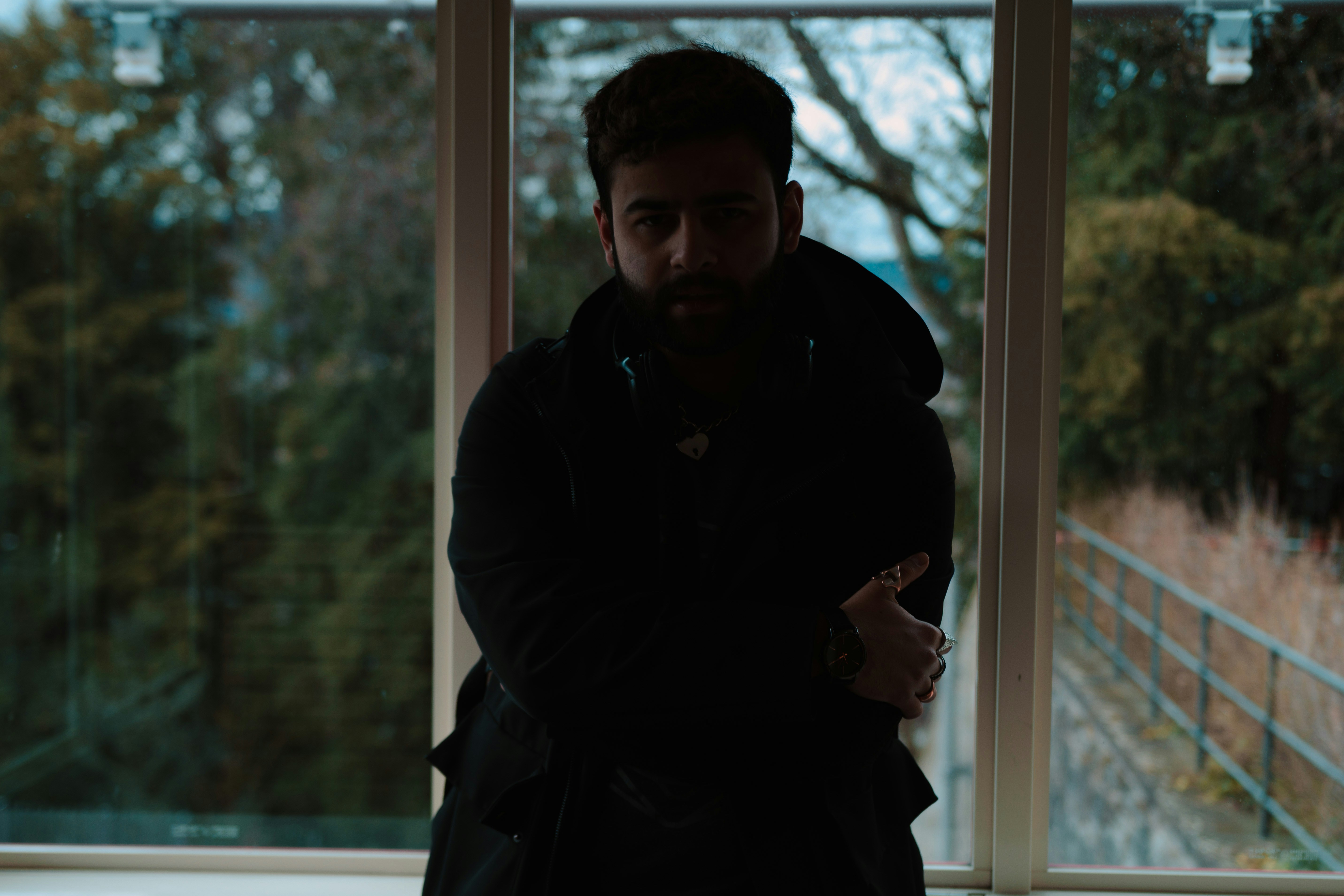 a man standing in front of a window with his arms crossed
