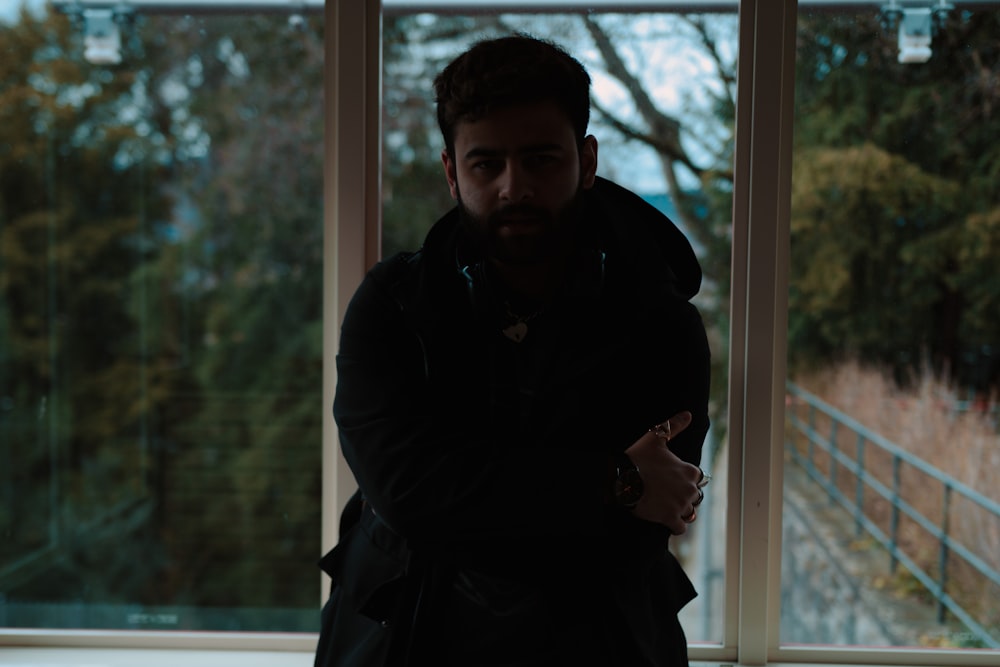 a man standing in front of a window with his arms crossed