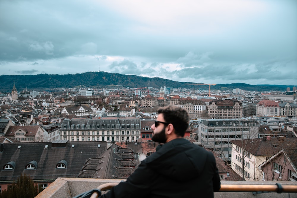 a man sitting on a ledge overlooking a city