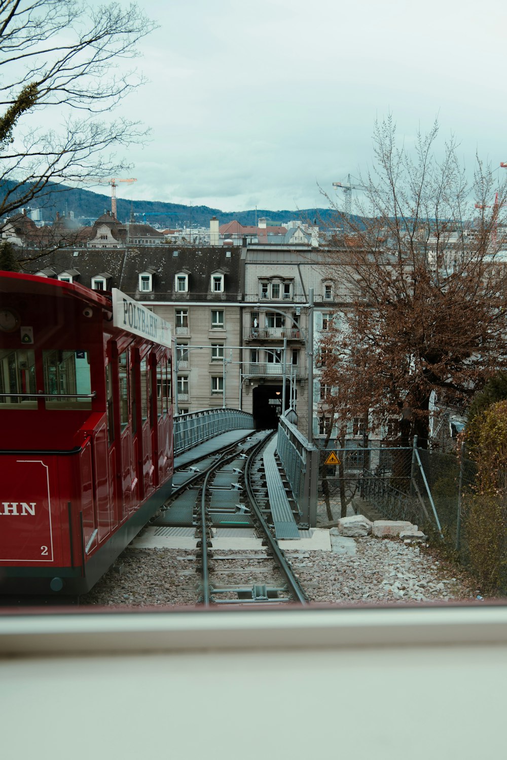 a red train traveling down train tracks next to a tall building