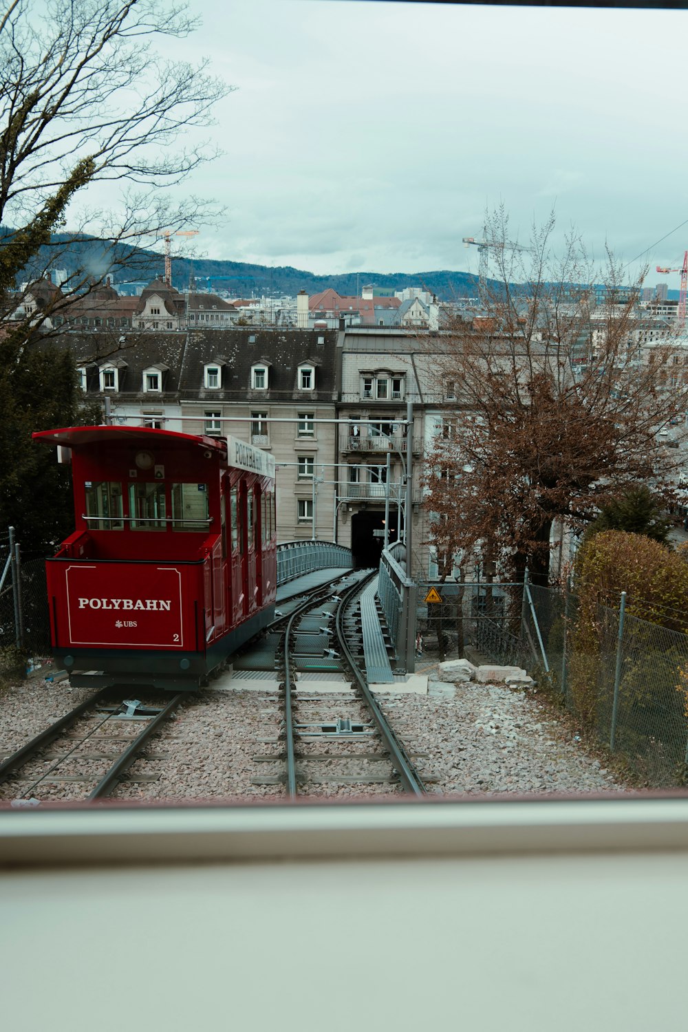 a red train traveling down train tracks next to a tall building