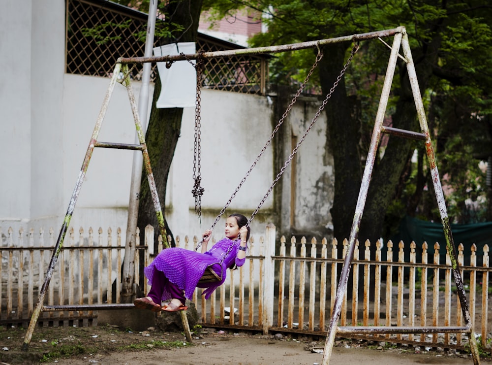 uma mulher em um vestido roxo balançando em um conjunto de balanço
