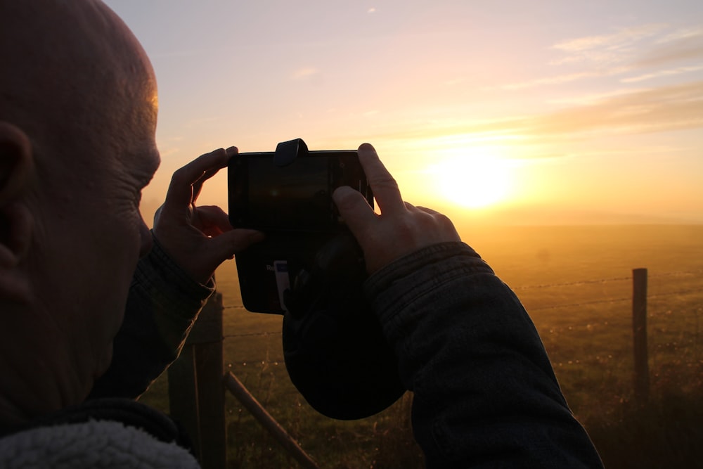 a man taking a picture of a sunset with a camera