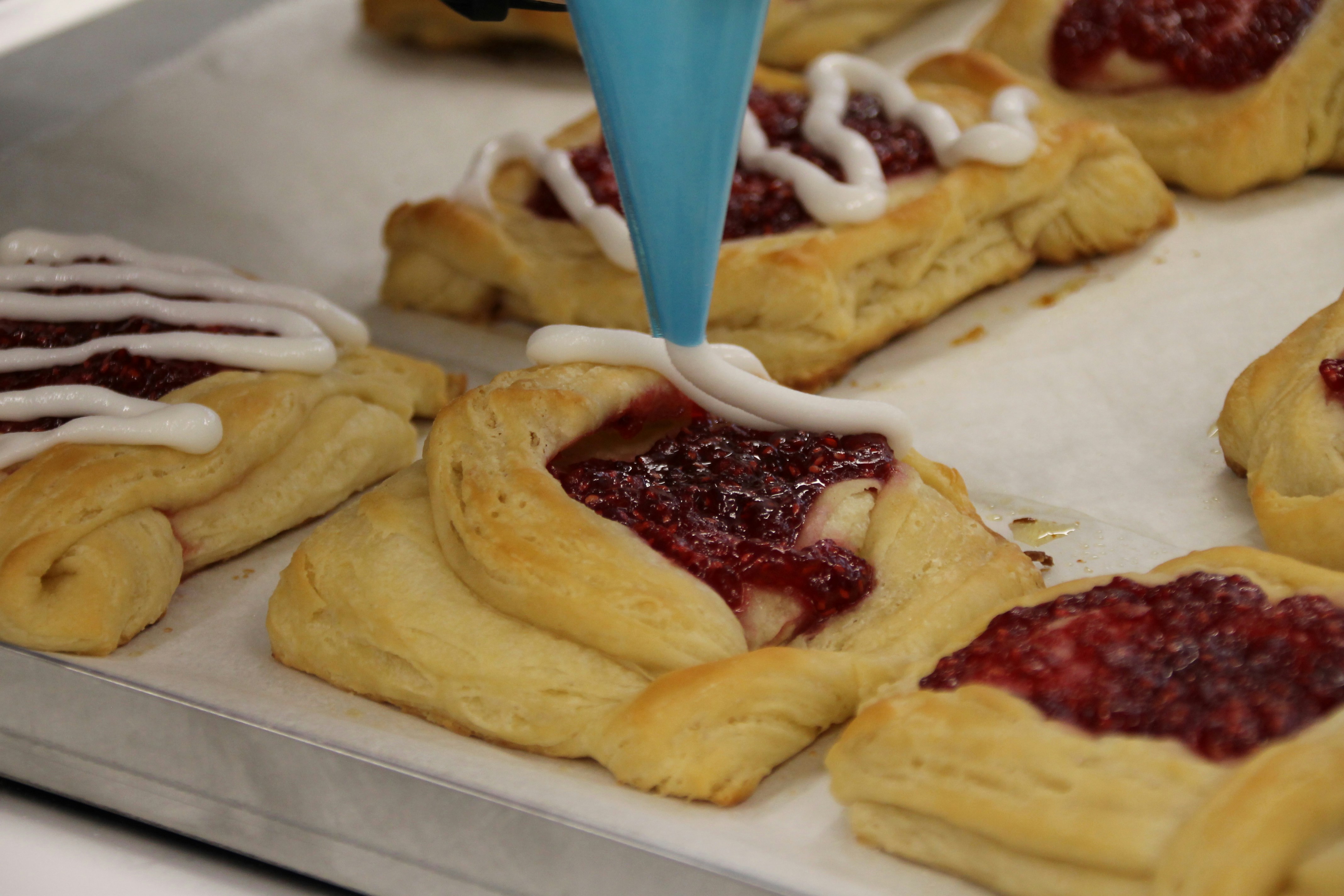 a person is spreading icing on pastries on a tray