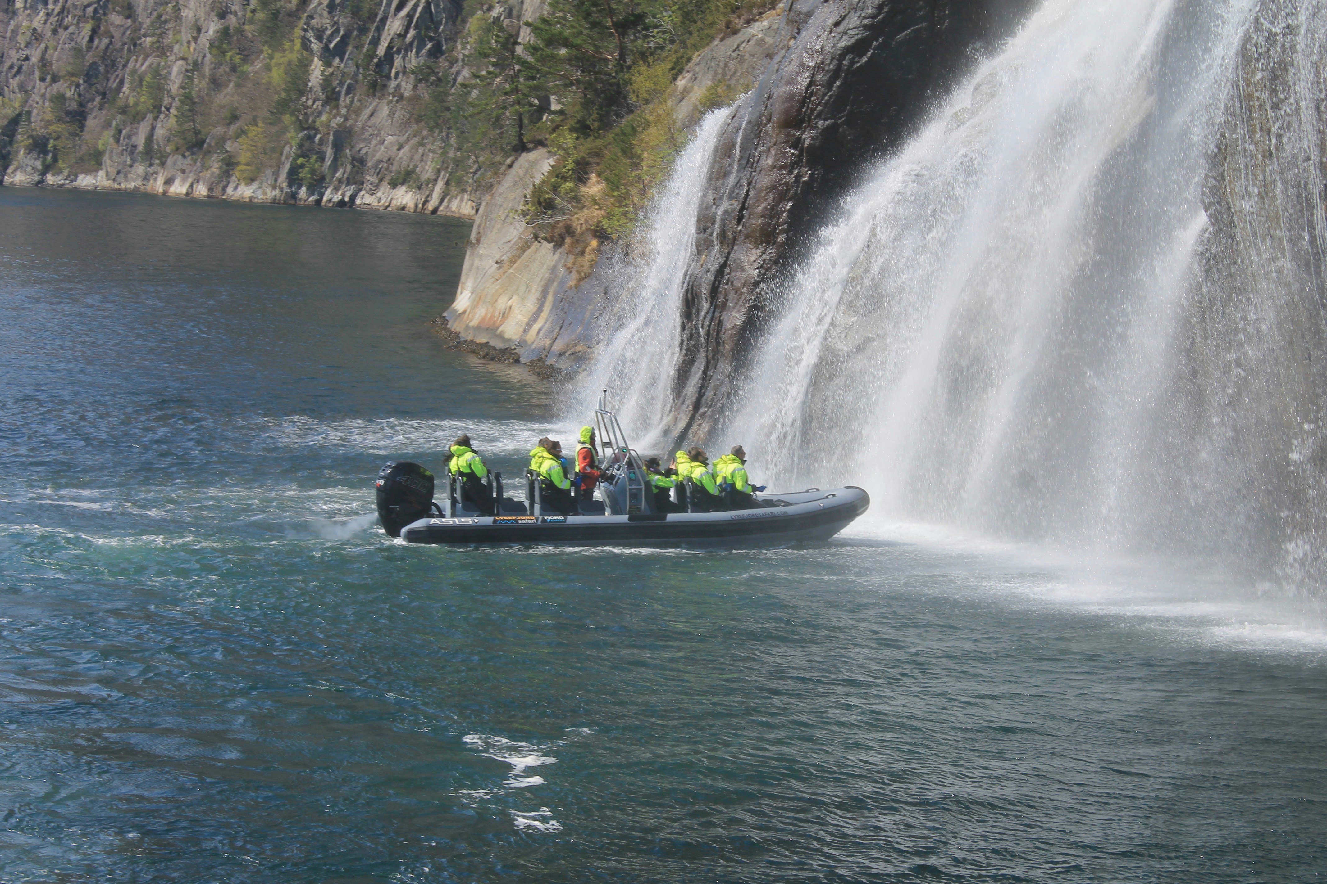 Eine Gruppe von Menschen auf einem Boot vor einem Wasserfall