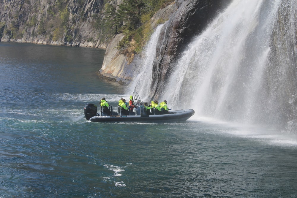 a group of people on a boat in front of a waterfall