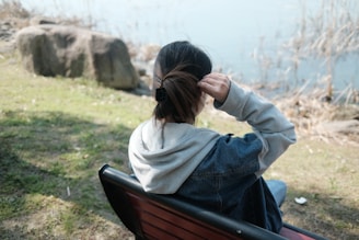 a woman sitting on top of a wooden bench