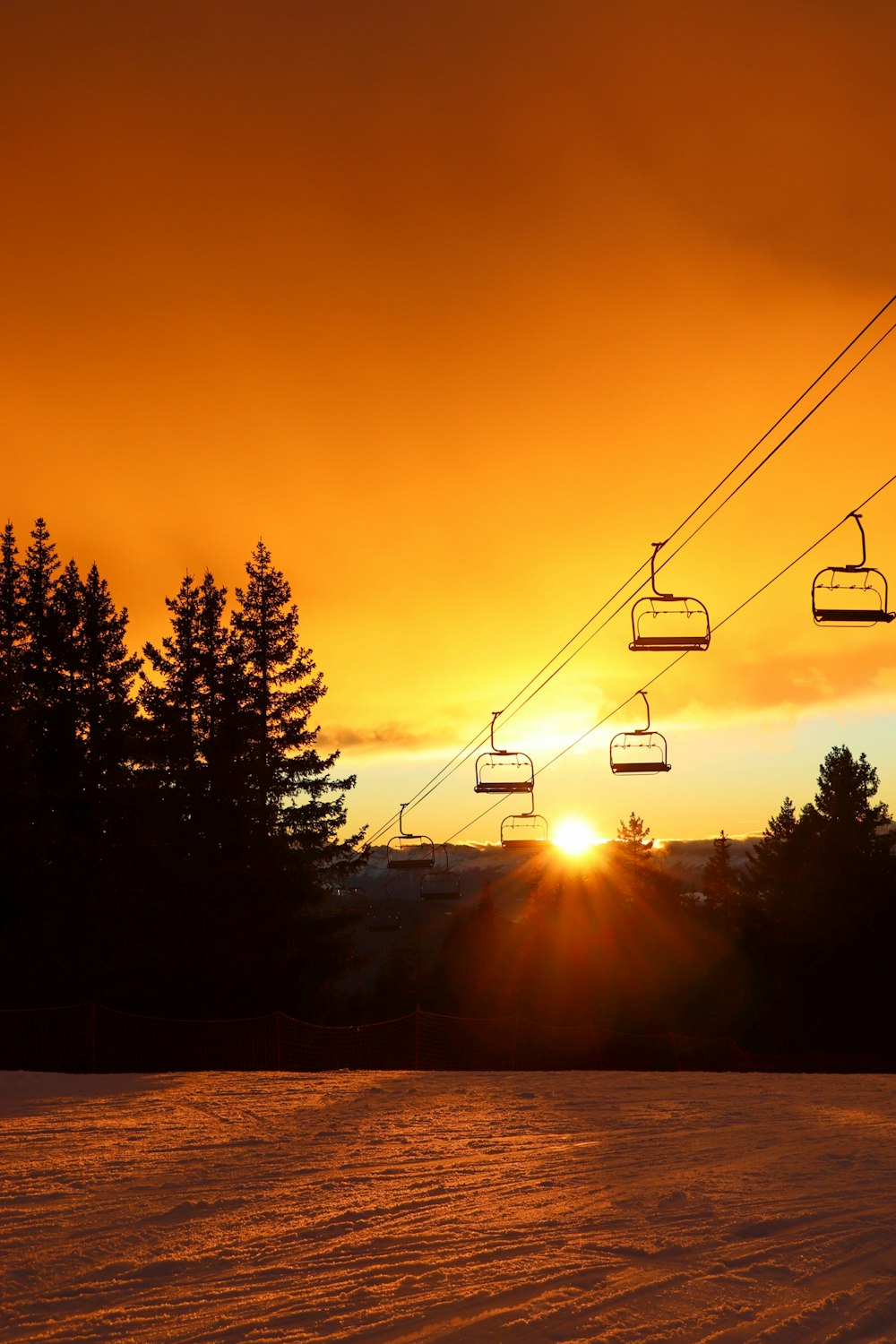 the sun is setting behind a ski lift