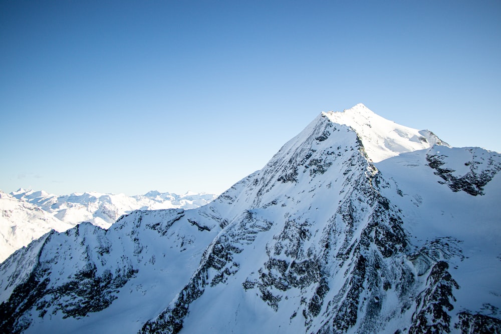 a large mountain covered in snow under a blue sky