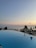 Guests relaxing by an infinity pool overlooking a vibrant sunset at a luxury resort.