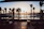 Evening shot of a luxury screened lanai glowing softly under palm trees with a sunset sky in the background.