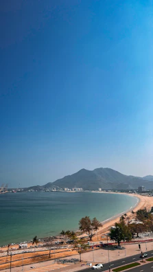 A panoramic view of Dili’s coastline with turquoise waters and palm trees under a bright sky.