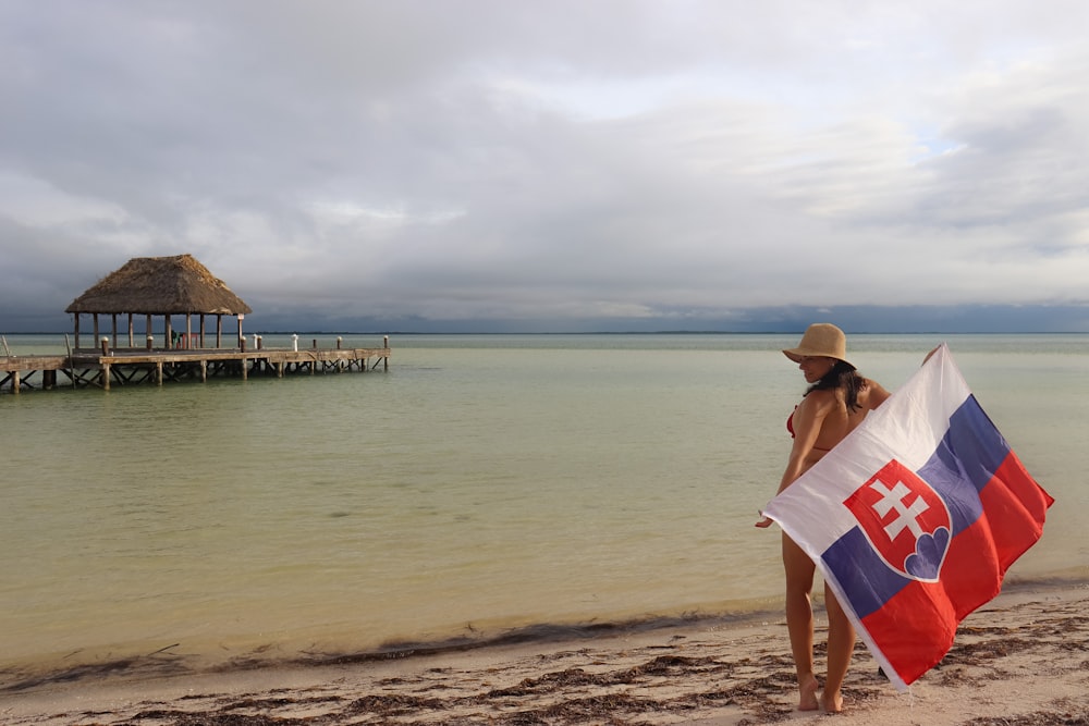 a woman standing on a beach holding a flag