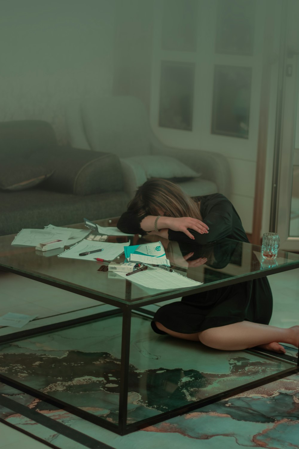 a woman sitting on the floor in front of a glass table