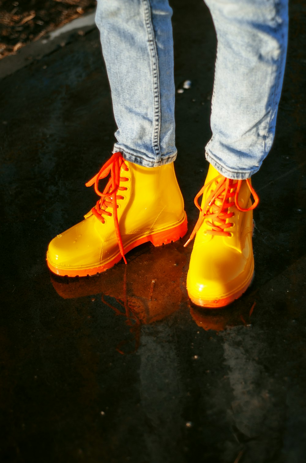 a person wearing yellow rain boots standing on a wet surface