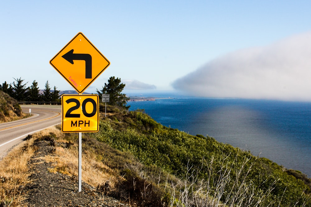 a road sign on the side of a road next to a body of water