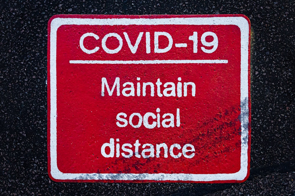 a red and white sign that says covidd - 19 maintain social distance