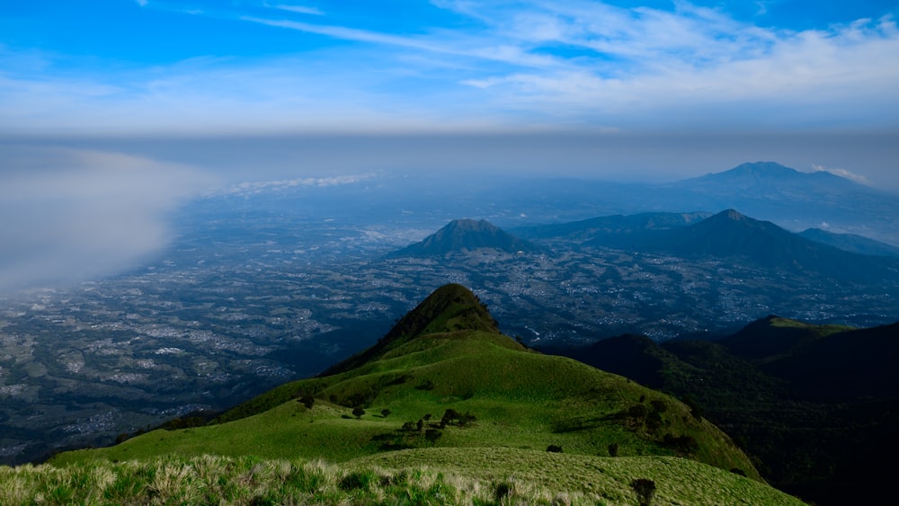 a view of a green mountain with a blue sky in the background