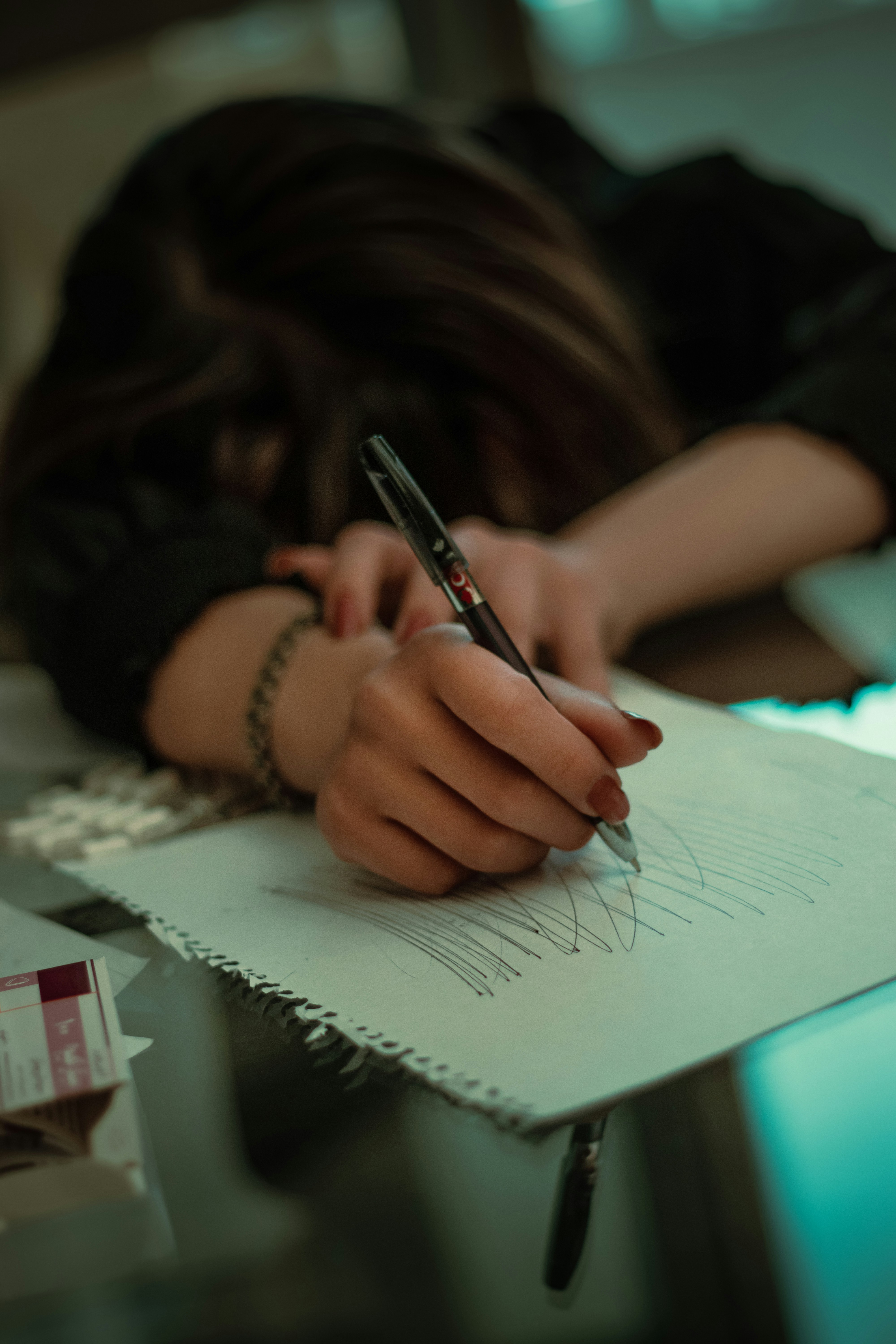 a woman writing on a piece of paper with a pen