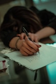 a woman writing on a piece of paper with a pen