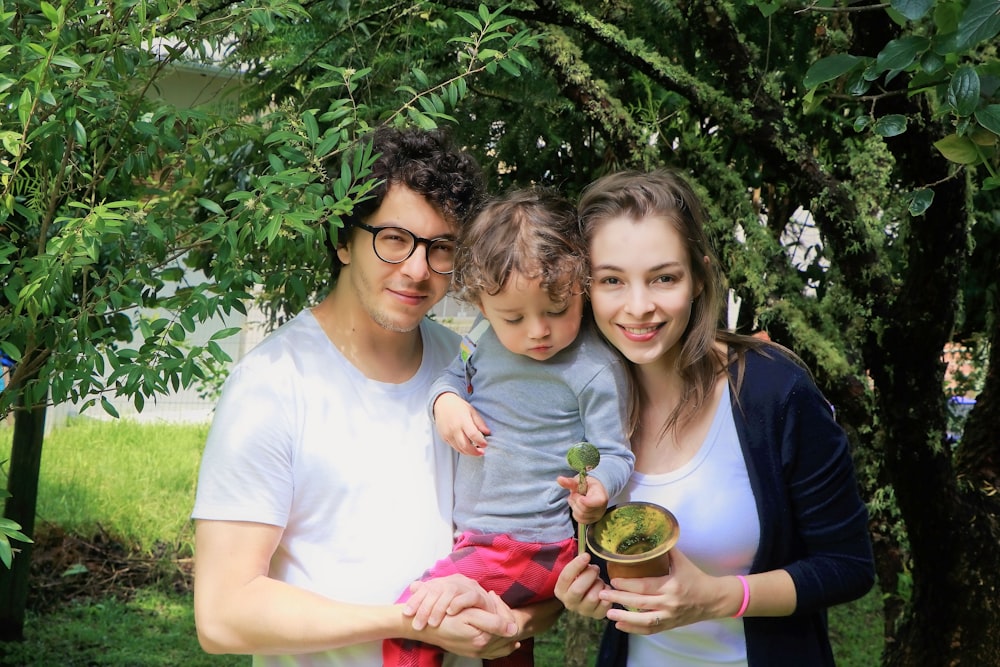 a man and a woman holding a baby and a potted plant