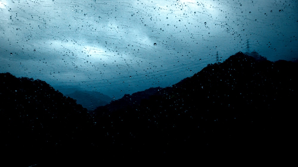 a view of a mountain range through a rain covered window