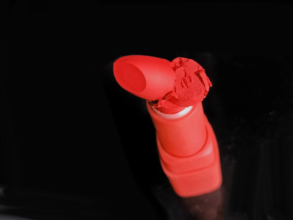 a red tube of lipstick sitting on top of a table