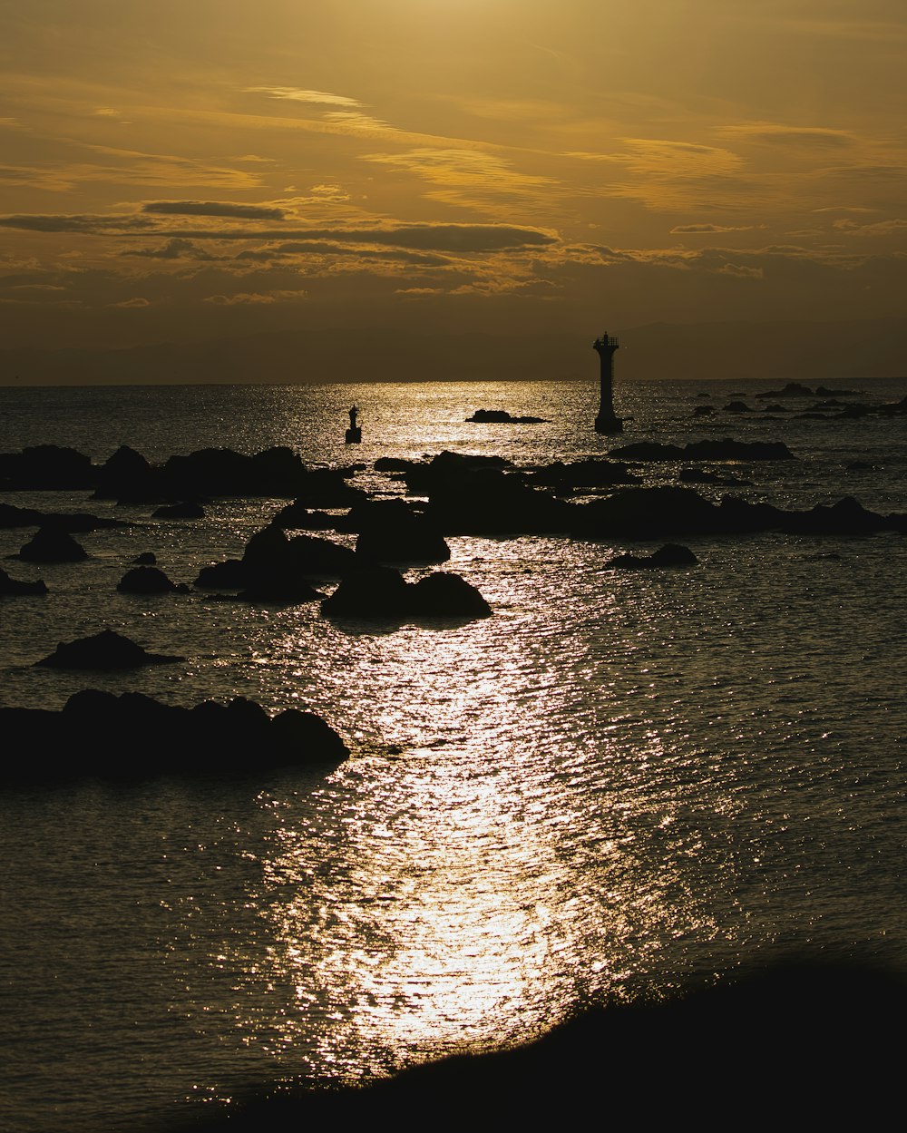 Una persona parada sobre rocas en el océano al atardecer