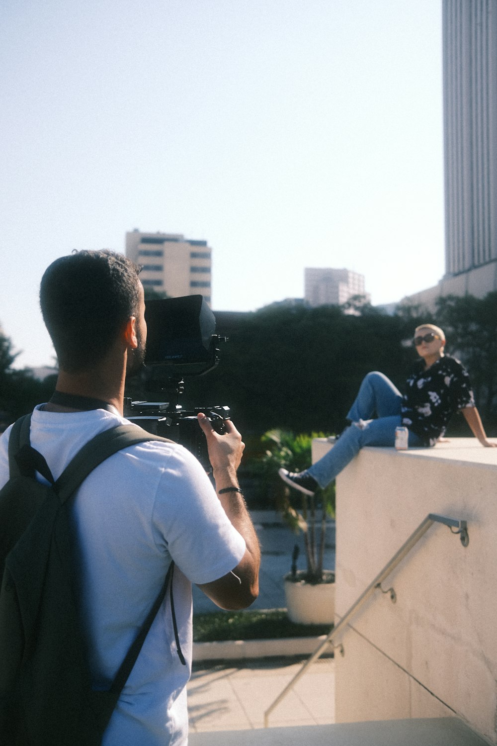 a man taking a picture of another man sitting on a ledge