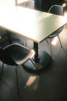 A minimalist dining setup by a window with soft sunlight casting gentle shadows.