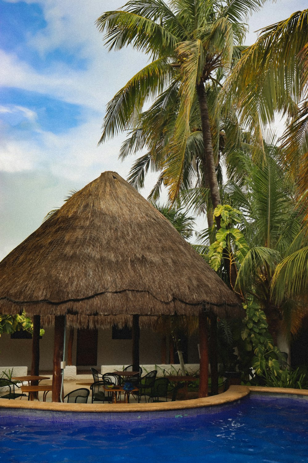 a thatched hut next to a swimming pool