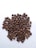A pile of roasted coffee beans spread out over a white surface, showcasing various shades of brown and some showing visible craters and cracks.