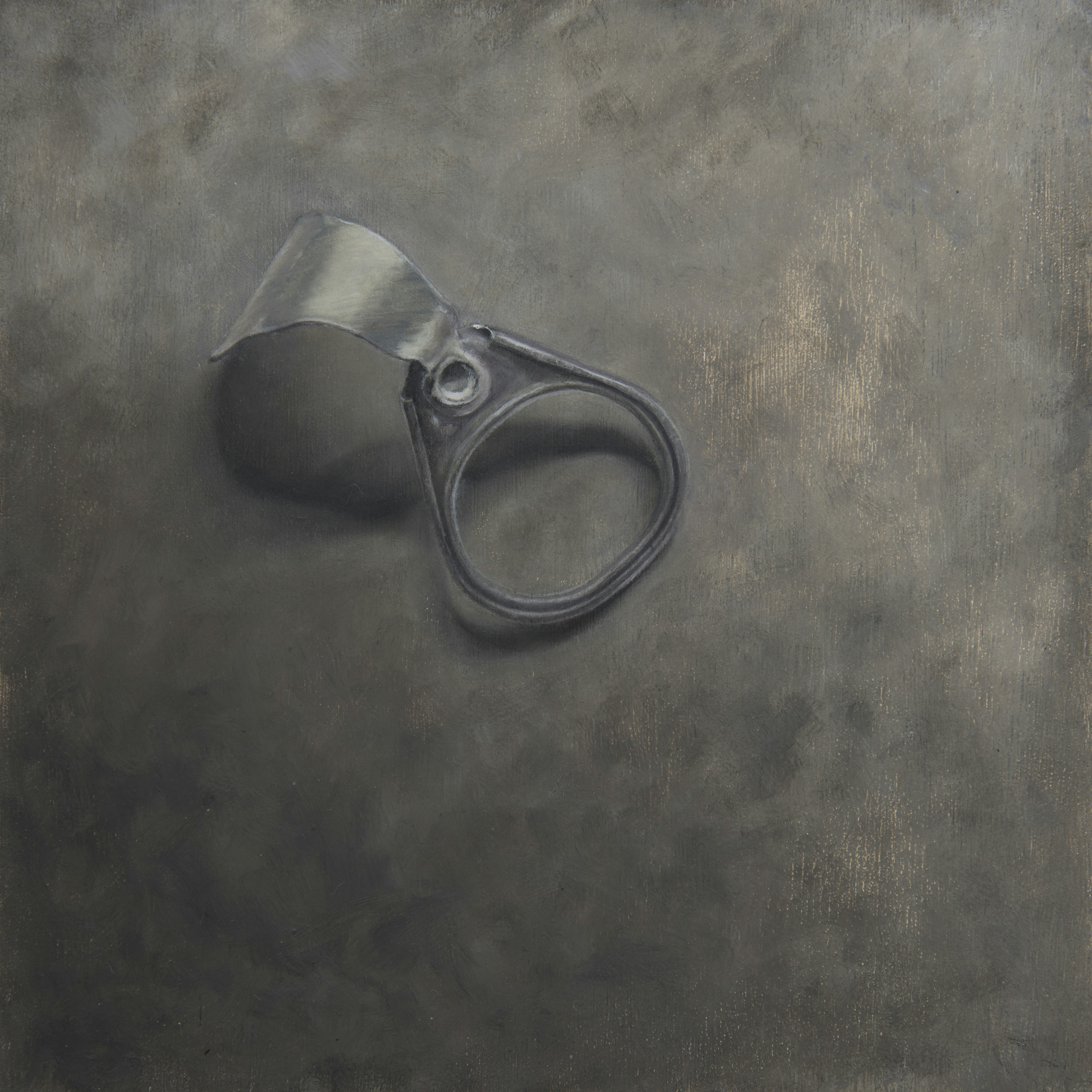 A photograph of a small black ring and strap resting on a textured, dark metal surface. The composition emphasizes the object's form and weathered texture.