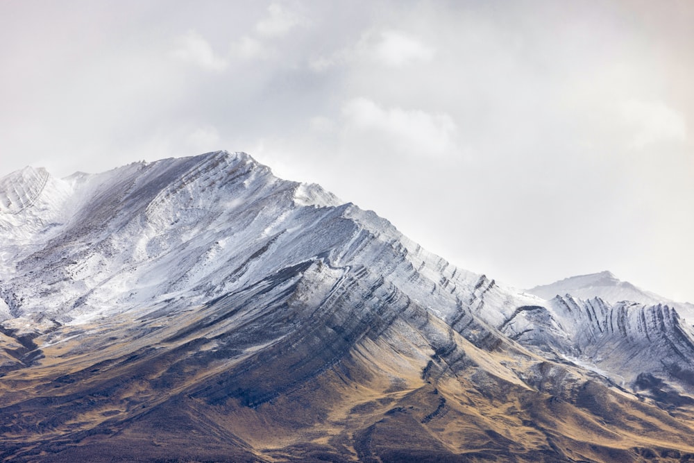 a large mountain covered in snow under a cloudy sky