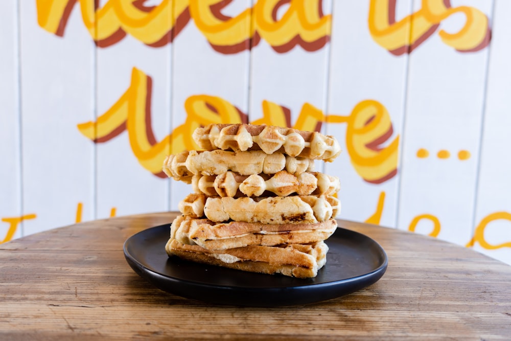 uma pilha de waffles sentados em cima de um prato preto