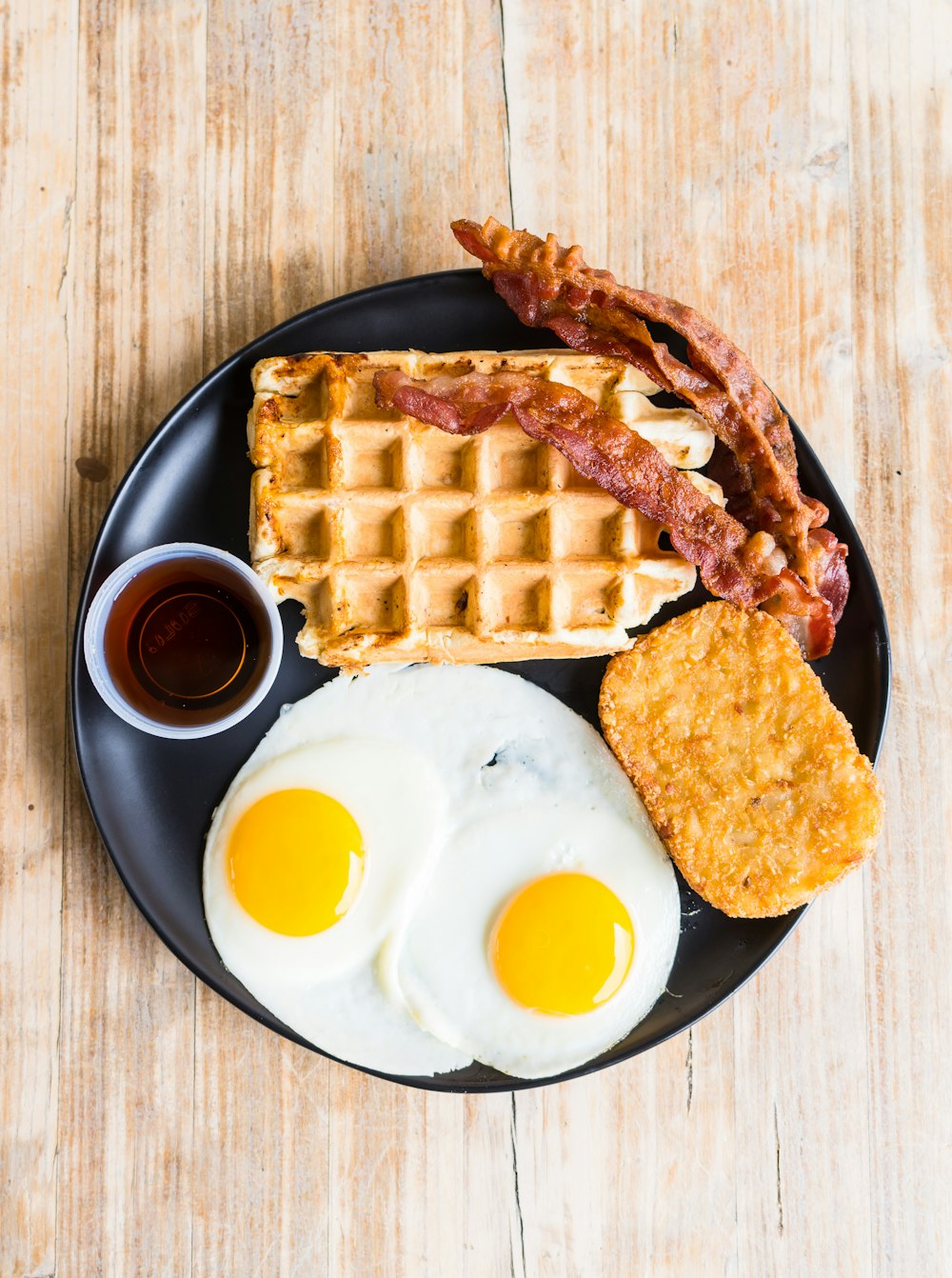 a breakfast plate with eggs, waffles, and bacon