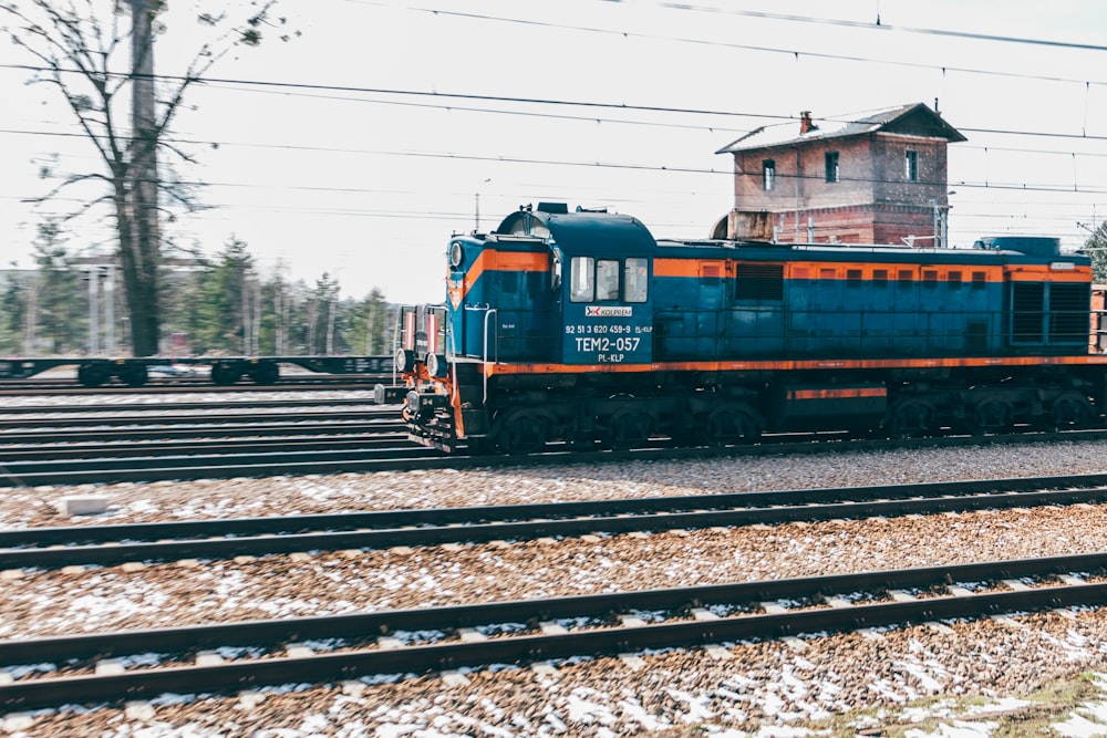 a blue and orange train traveling down train tracks