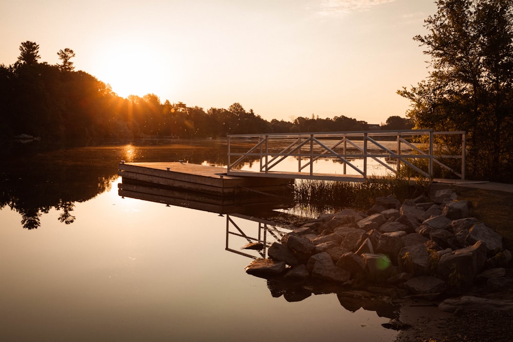 a dock sitting next to a lake at sunset