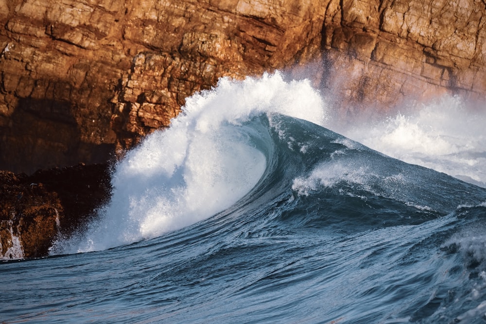 a large wave crashing into a rocky cliff