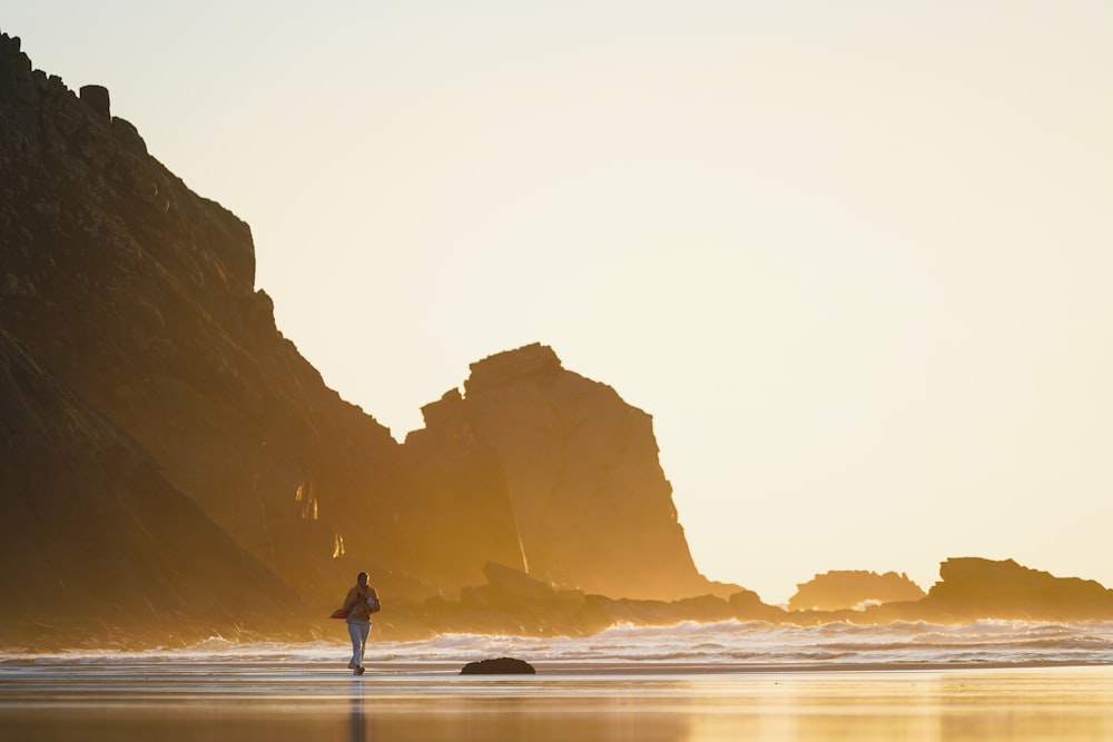 a person walking on the beach at sunset