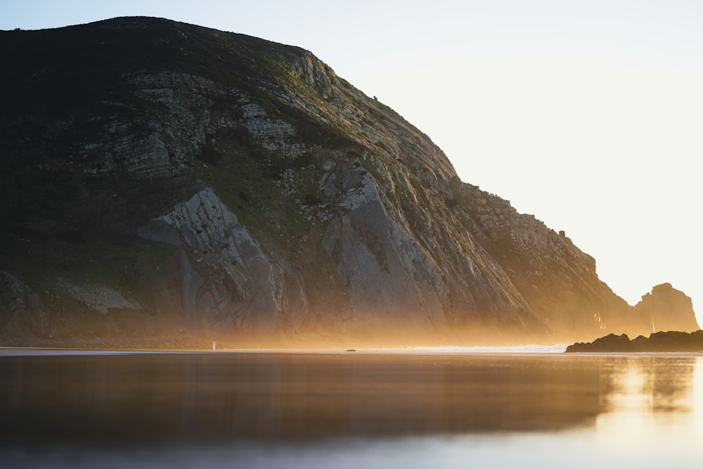 a large mountain sitting next to a body of water