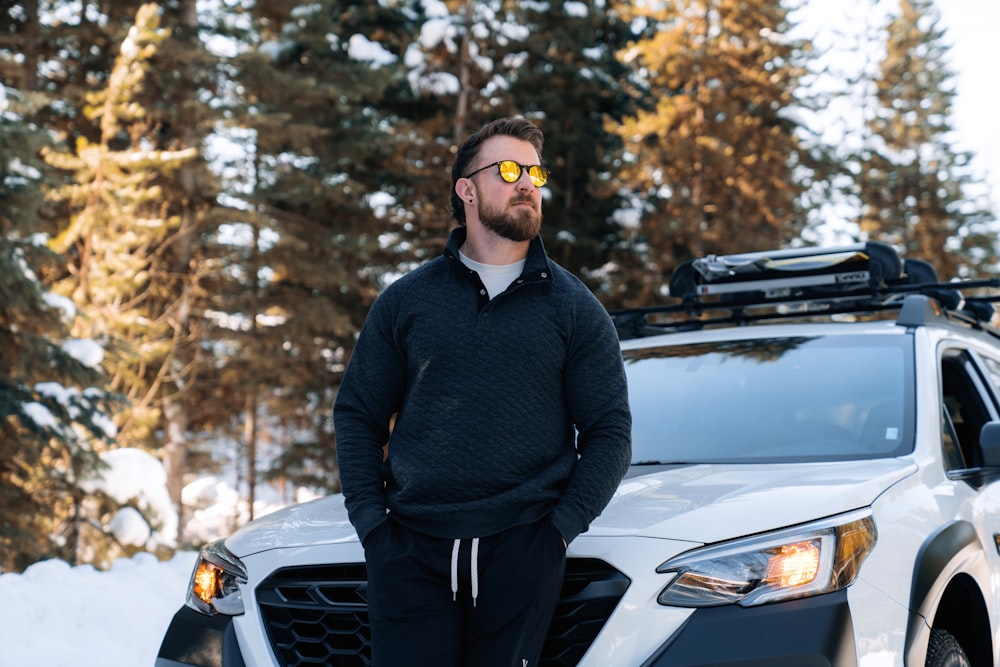 a man standing in front of a car in the snow