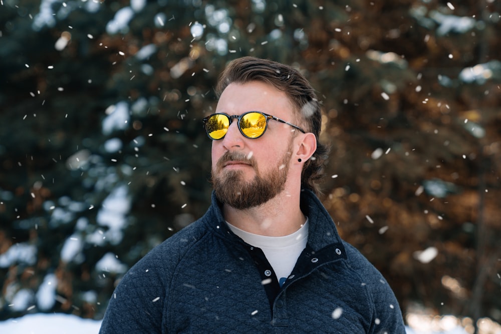 a man wearing yellow sunglasses standing in the snow