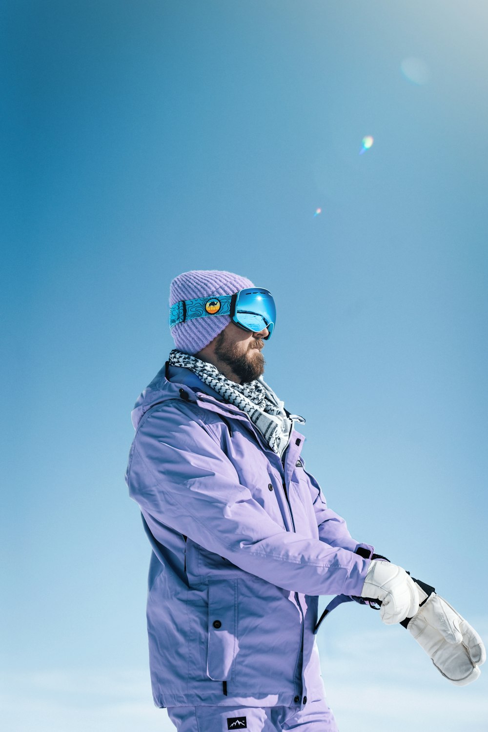 a man in a purple jacket and goggles holding a snowboard
