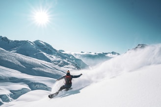 a man riding a snowboard down the side of a snow covered slope