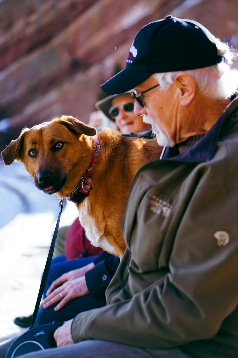 a man sitting next to a woman with a dog on a leash