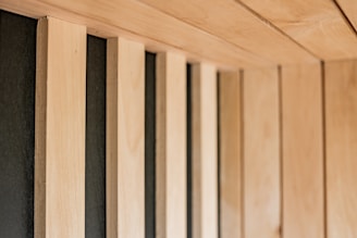 A series of vertical wooden panels alternating with dark-colored gaps create a visually striking pattern. The panels extend across the frame, showcasing a minimalist and modern design.