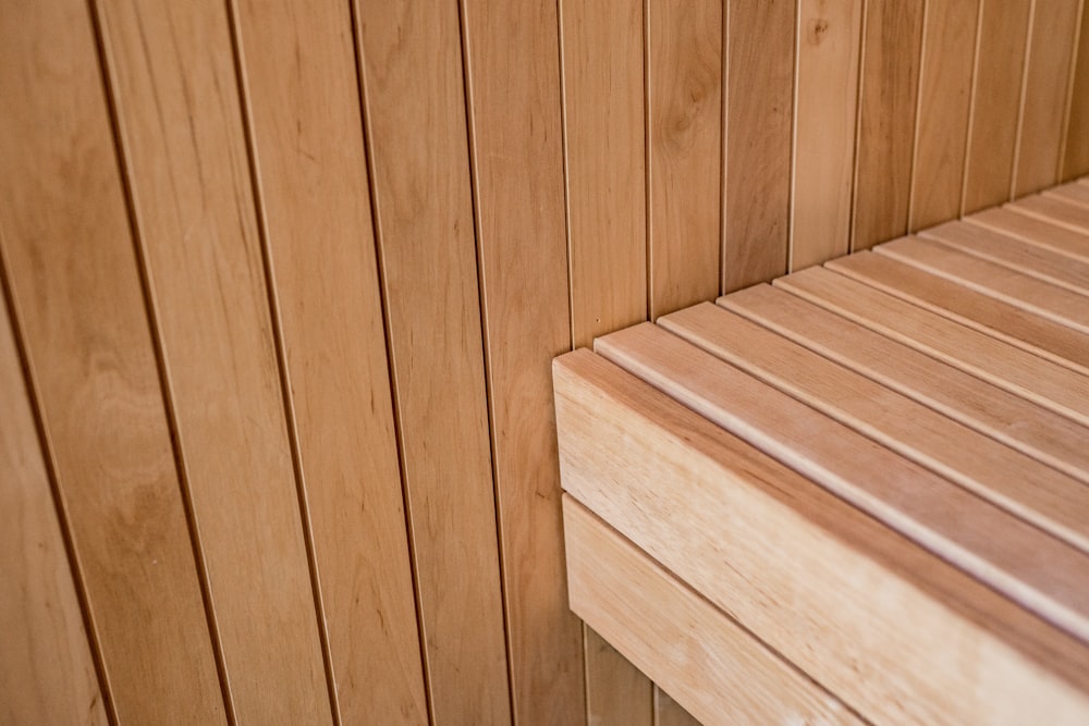 a close up of a wooden bench against a wall